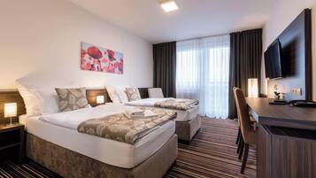 Habitación de hotel con dos camas, un escritorio, una silla, un televisor y un cuadro en la pared.