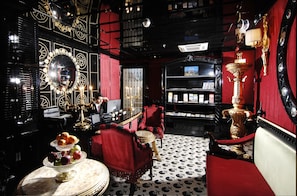 A room with a red and black color scheme, a chandelier, a mirror, a red sofa, and a table with fruit. - Premist Hotels Sultanahmet (Istanbul)