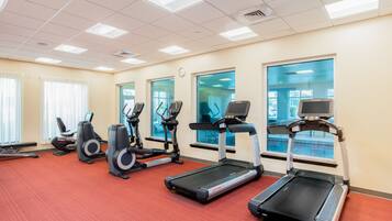 A fitness room with treadmills, elliptical machines, and stationary bikes.
