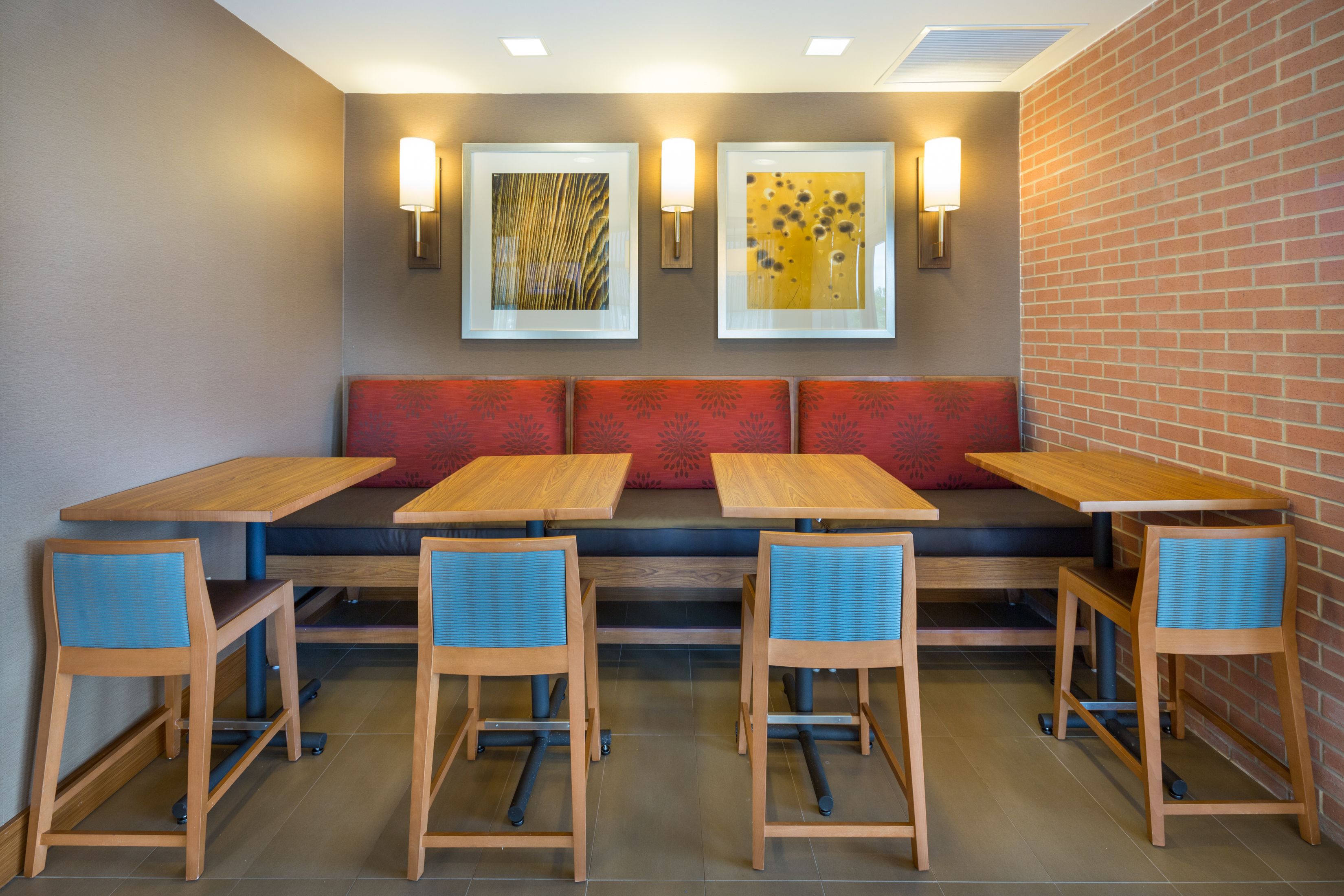 A restaurant with a booth seating area, wooden tables, and blue chairs.