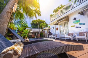 A poolside area with lounge chairs, a small pool, and a white building with a balcony. - Seascape Tropical Inn - Adult Exclusive (Key West)