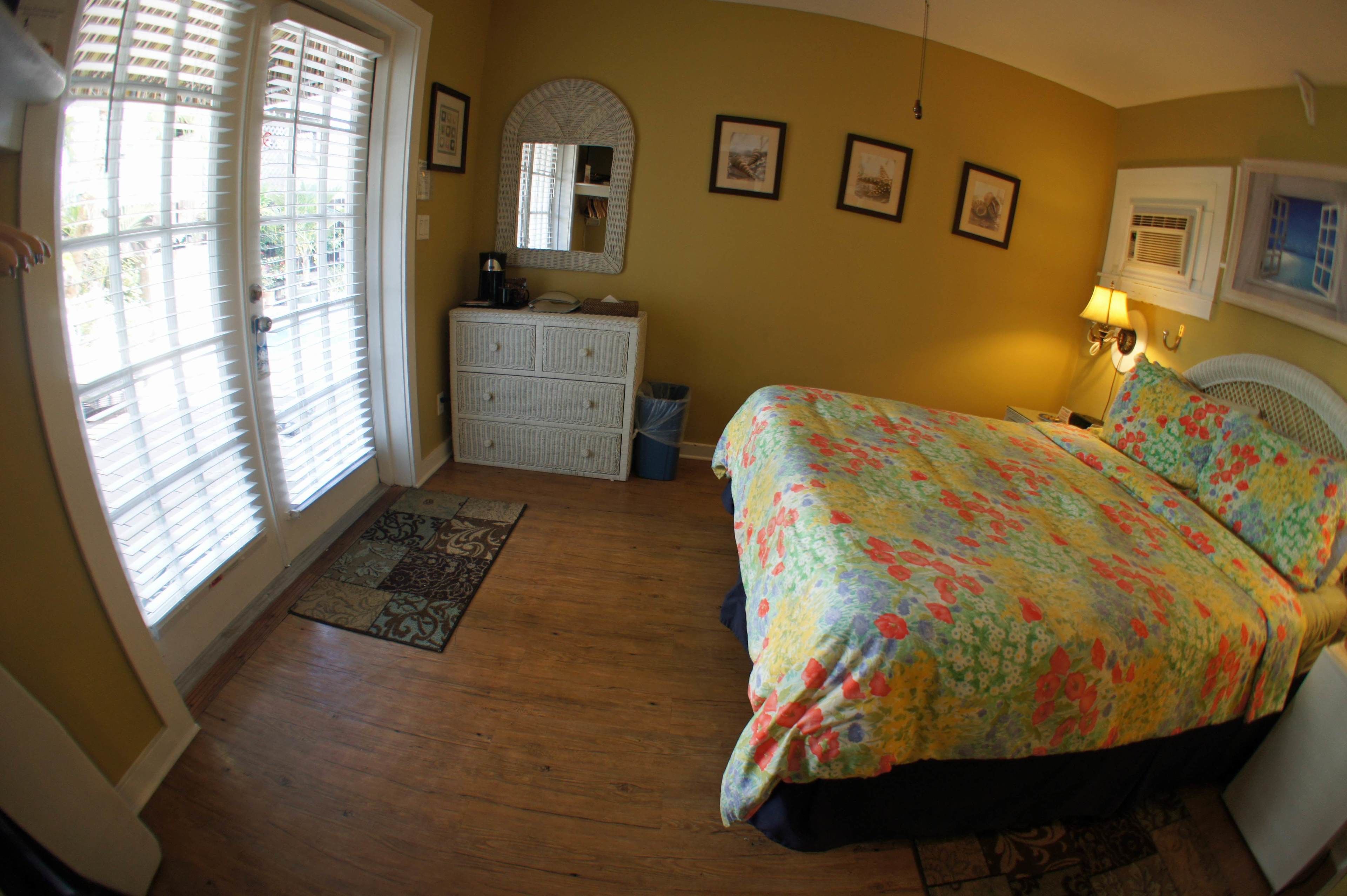 A bedroom with a bed, dresser, mirror, and a window with blinds.