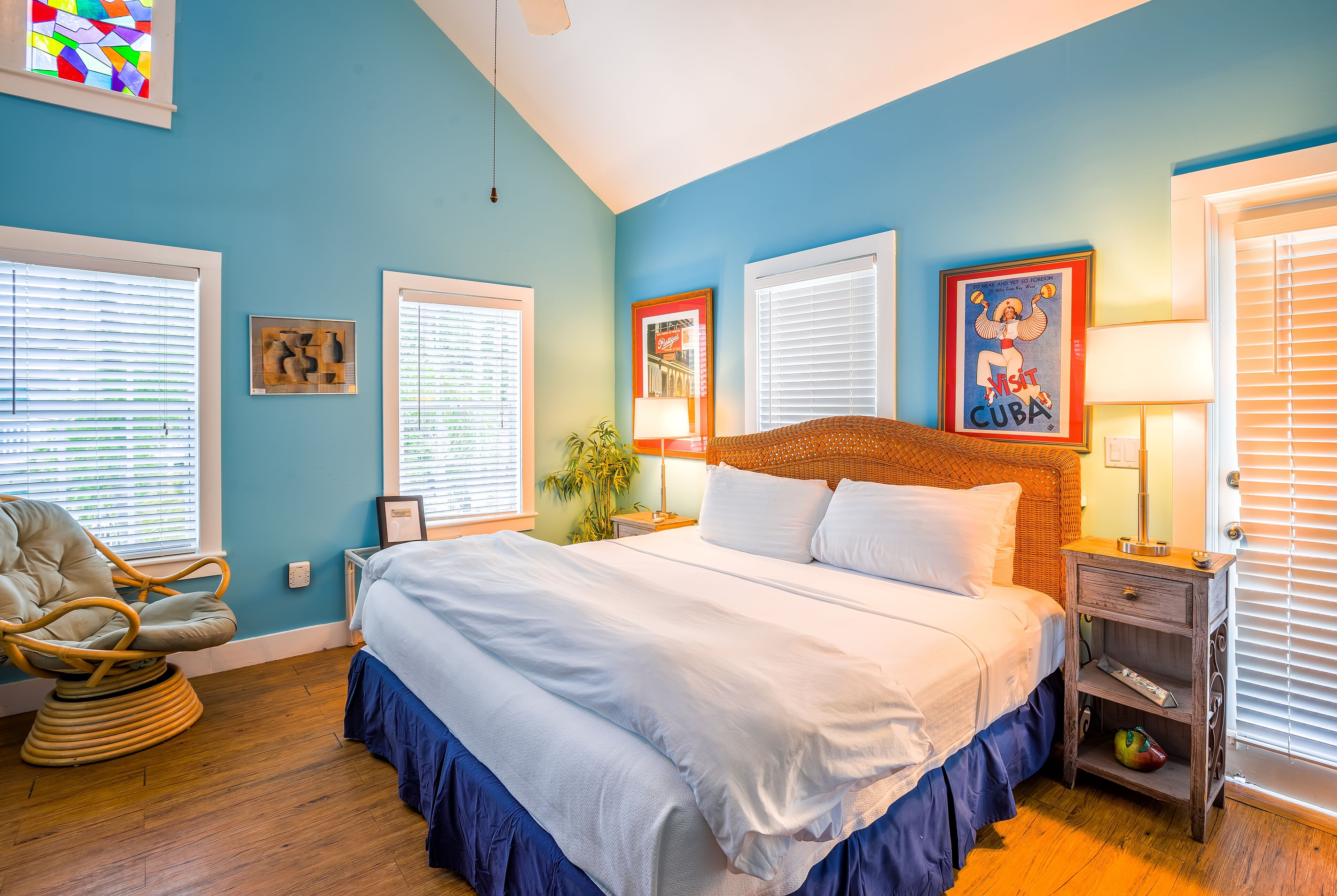 A bedroom with a large bed, a chair, and a nightstand with a lamp.