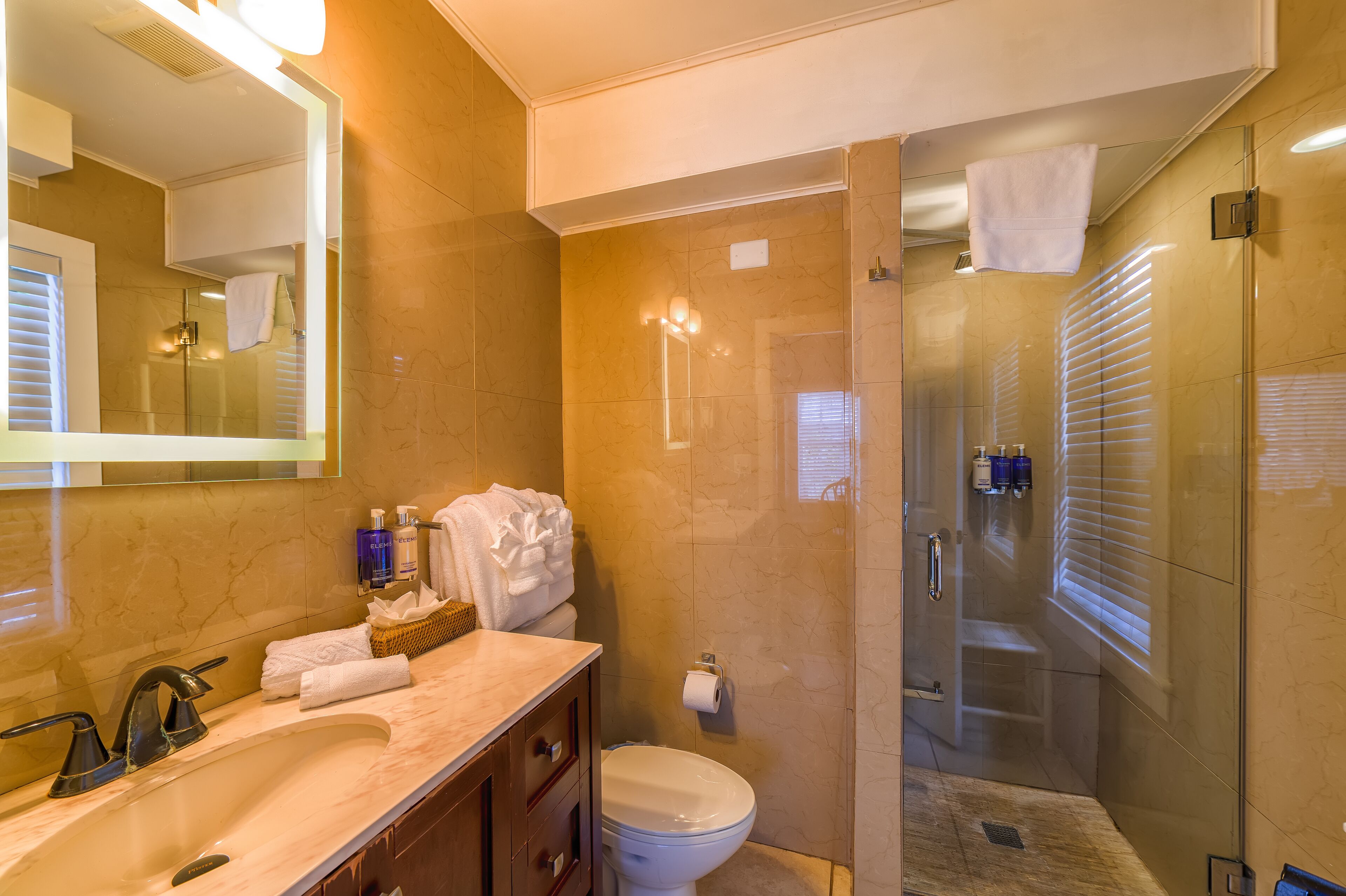 A modern bathroom with a marble sink, a glass-enclosed shower, and a large mirror.