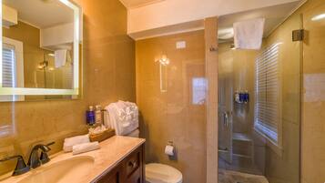 A modern bathroom with a marble sink, a glass-enclosed shower, and a large mirror.