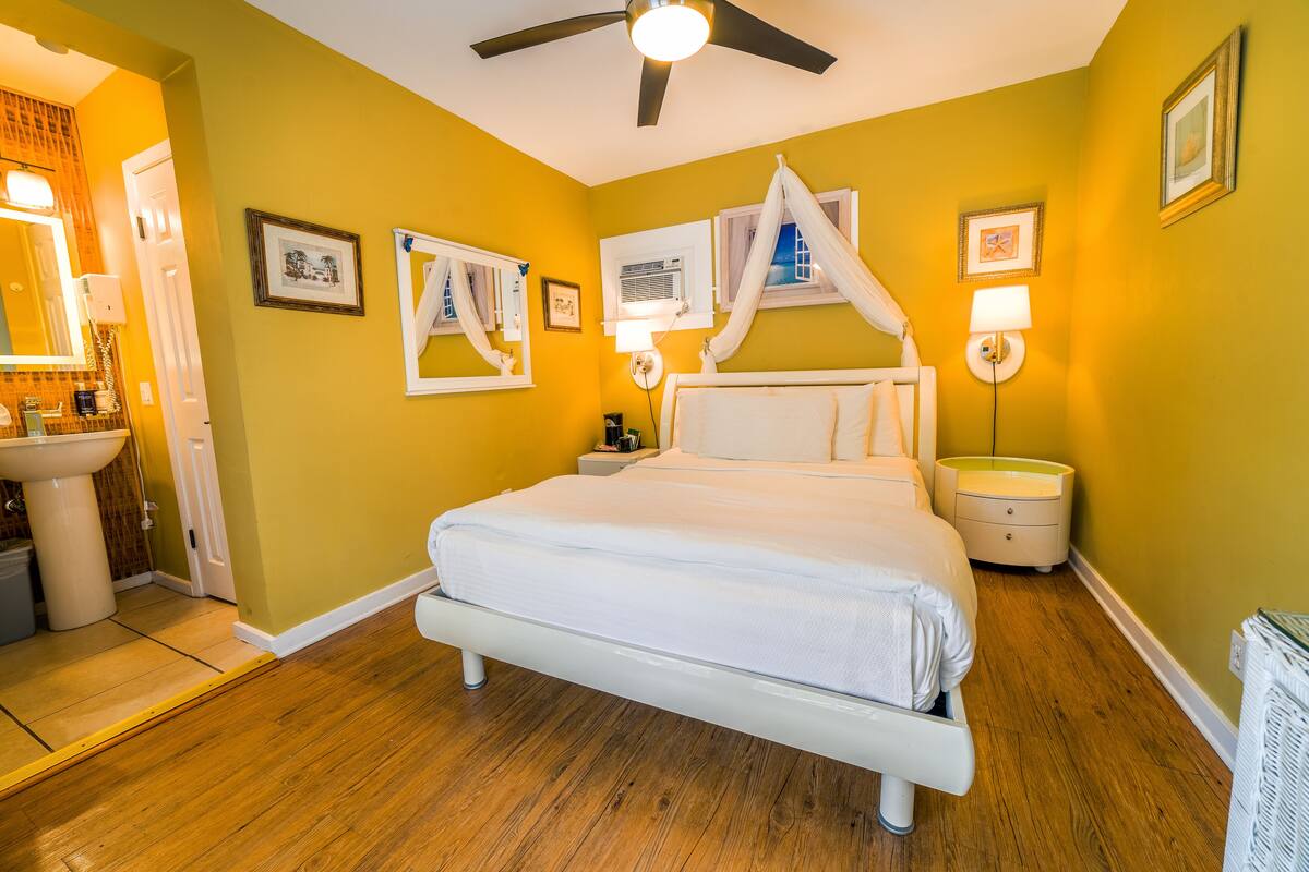 A bedroom with a bed, bedside tables, a ceiling fan, and a nightstand with a lamp.