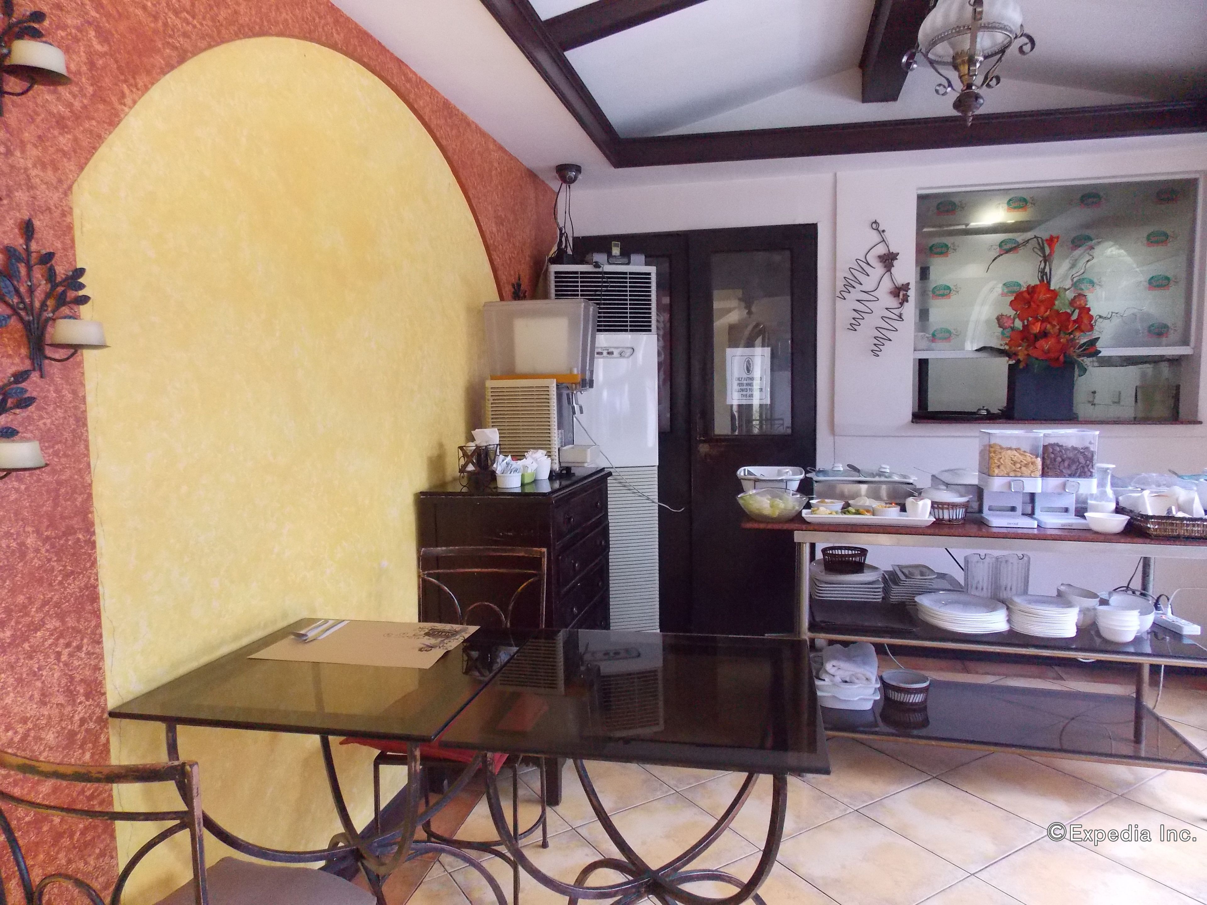 Een eetruimte met een glazen tafel, stoelen, een buffet met diverse gerechten en een decoratieve muur.