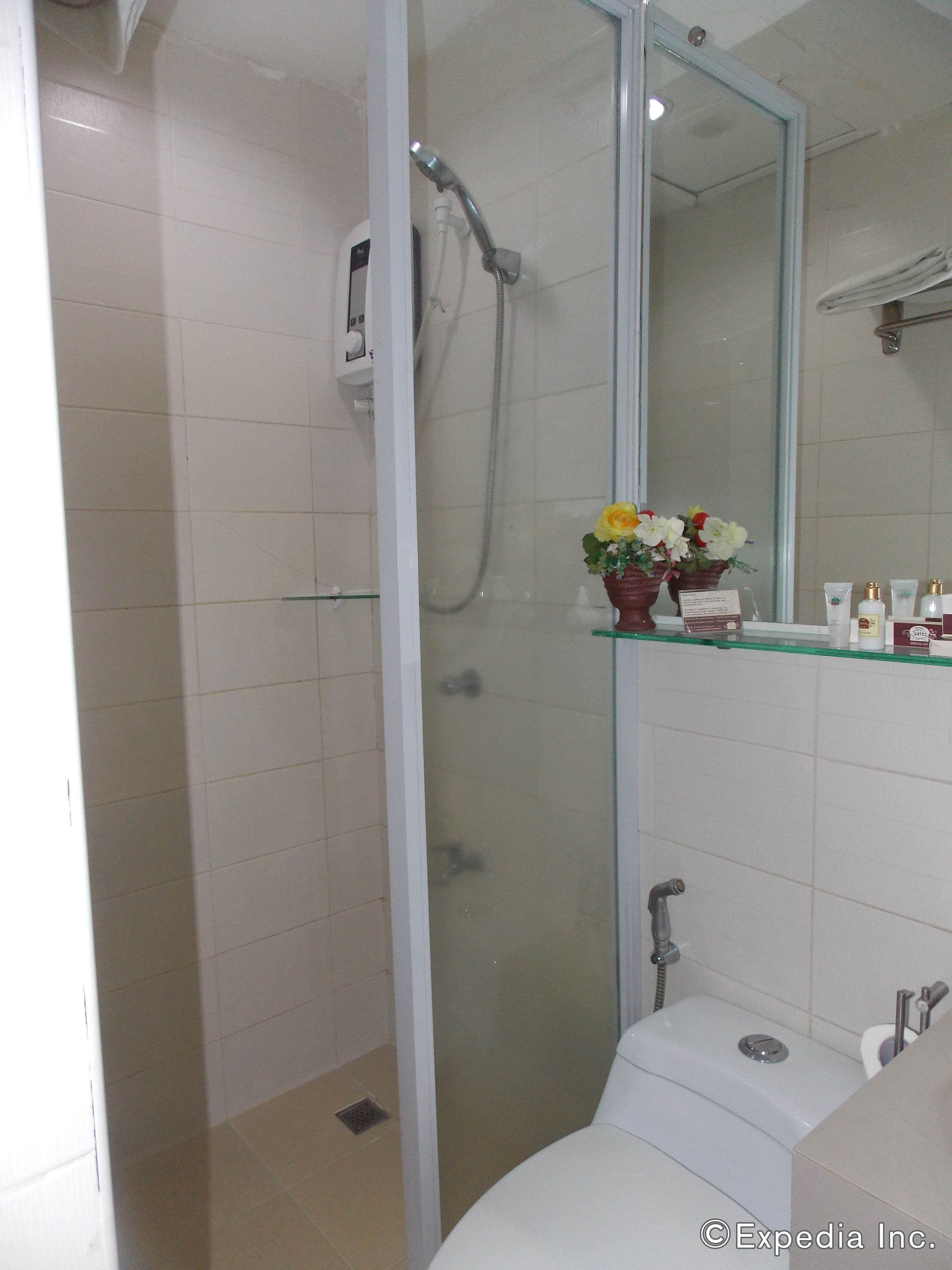 Un bagno con cabina doccia in vetro, un water e un lavandino con articoli da toilette.