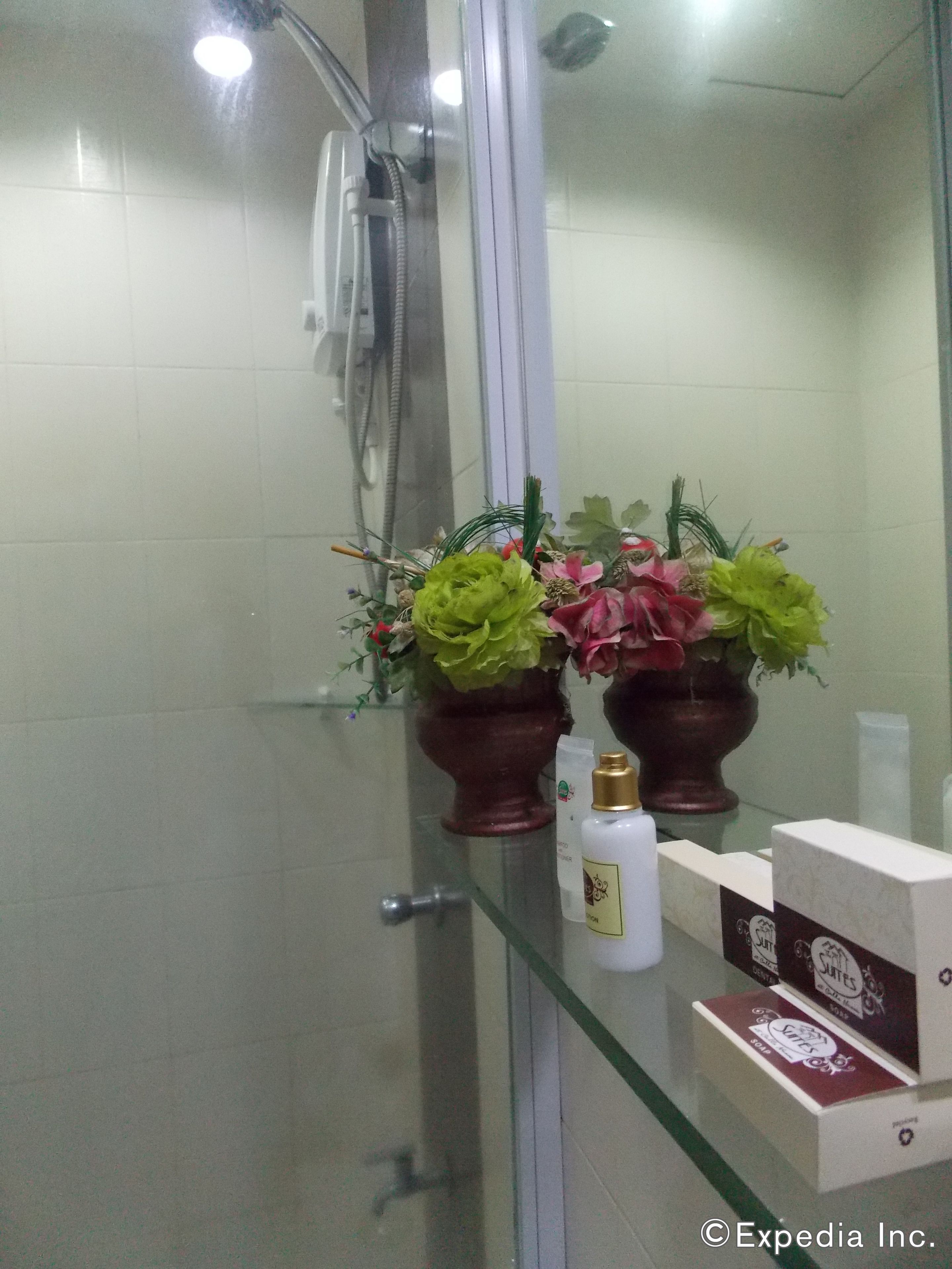 Ένα μπάνιο με ένα διαχωριστικό από γυαλί για το ντους, έναν καθρέφτη και είδη προσωπικής υγιεινής τοποθετημένα σε ένα ράφι.