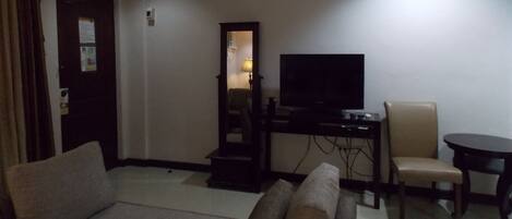 A living room with a sofa, a television on a stand, a chair, and a small table.