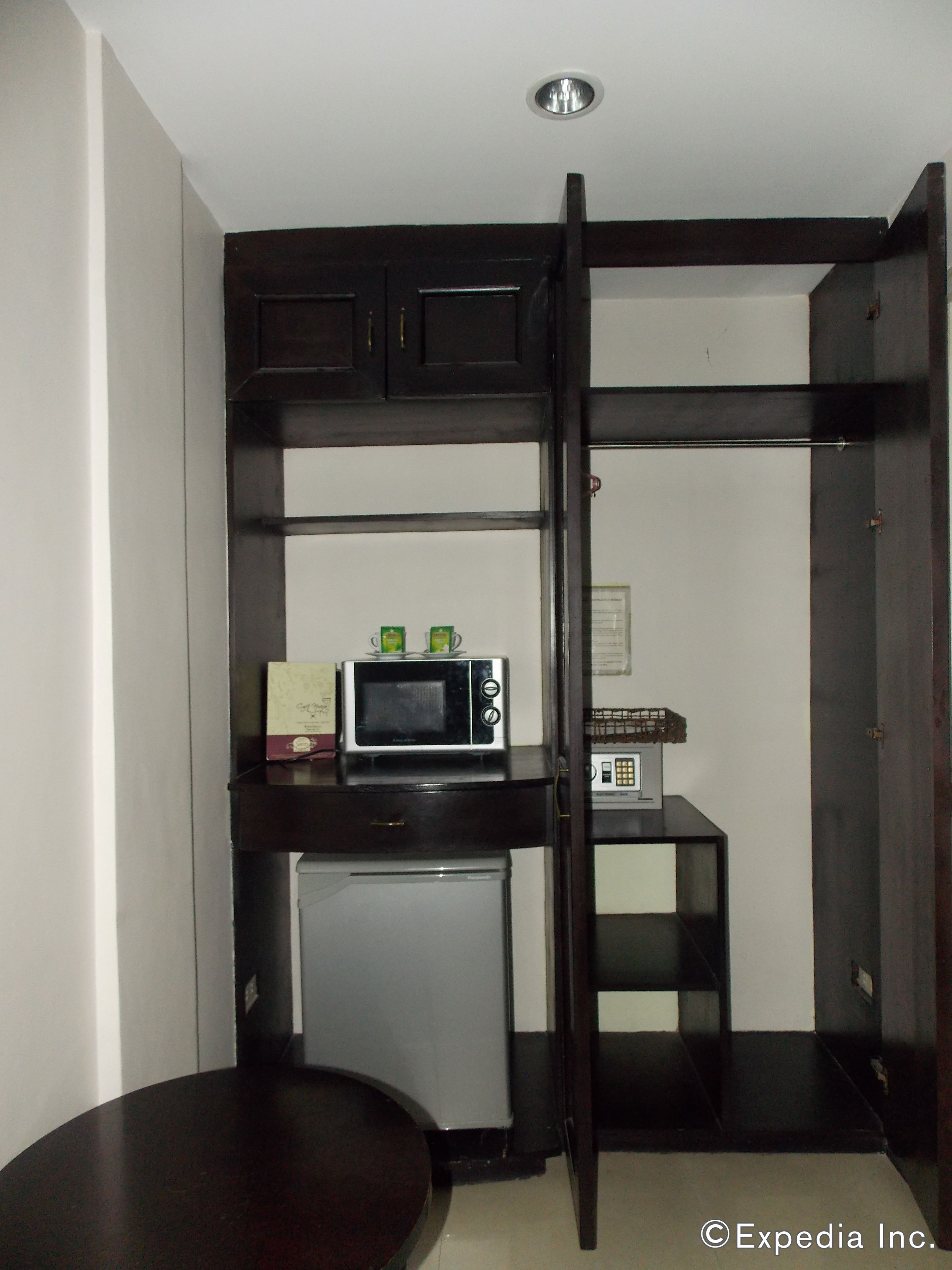 A compact kitchenette with a microwave, small refrigerator, and a coffee maker on a dark countertop.