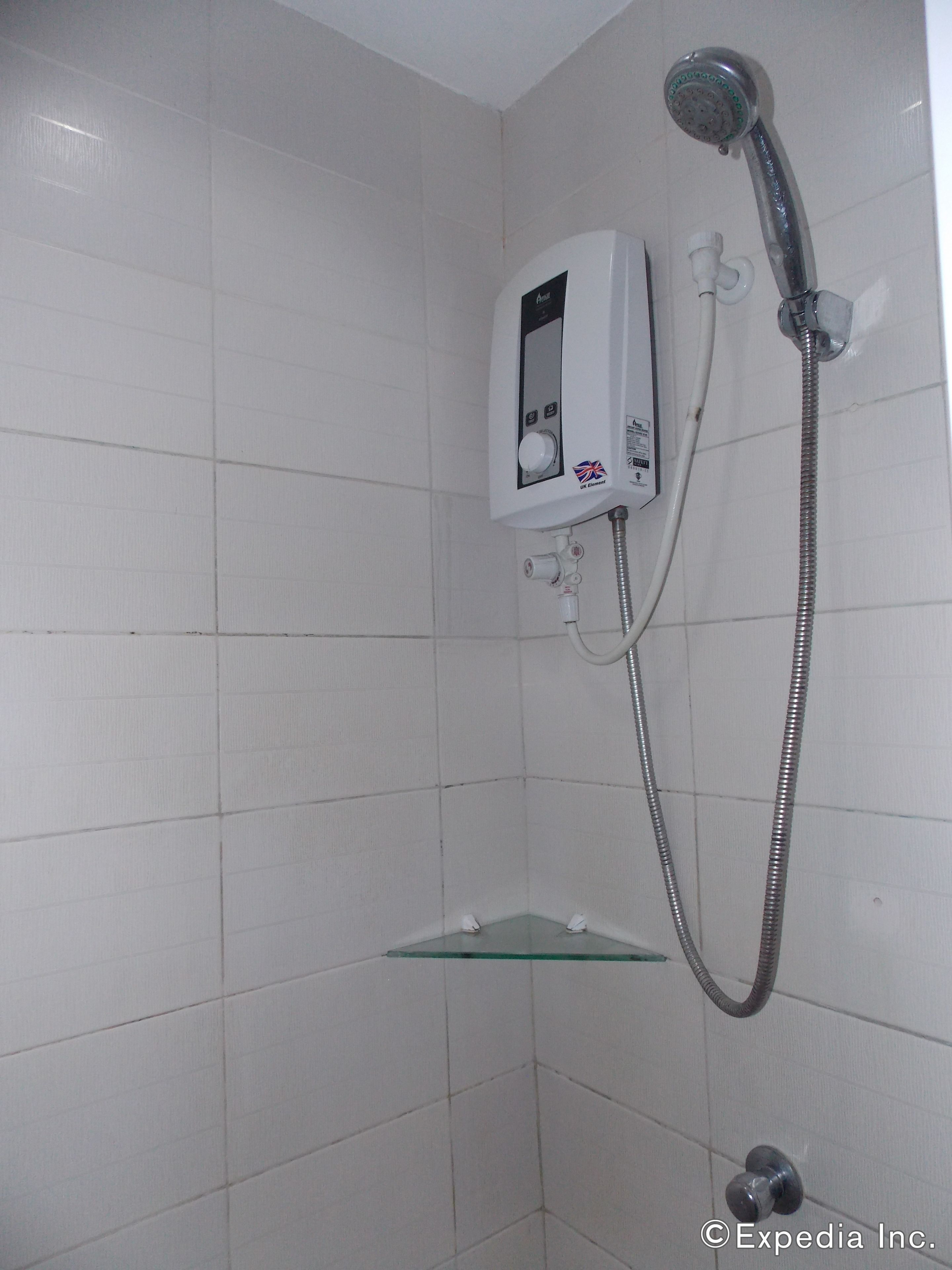A shower with a handheld showerhead and a wall-mounted control panel.