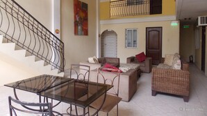 A spacious living area with a glass-top table, multiple sofas, and a staircase with a metal railing. - The Suites at Calle Nueva (Bacolod)