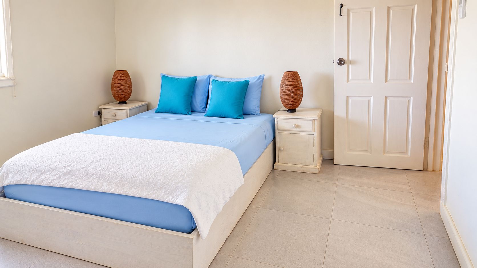 A bedroom with a bed, two nightstands, and a door.