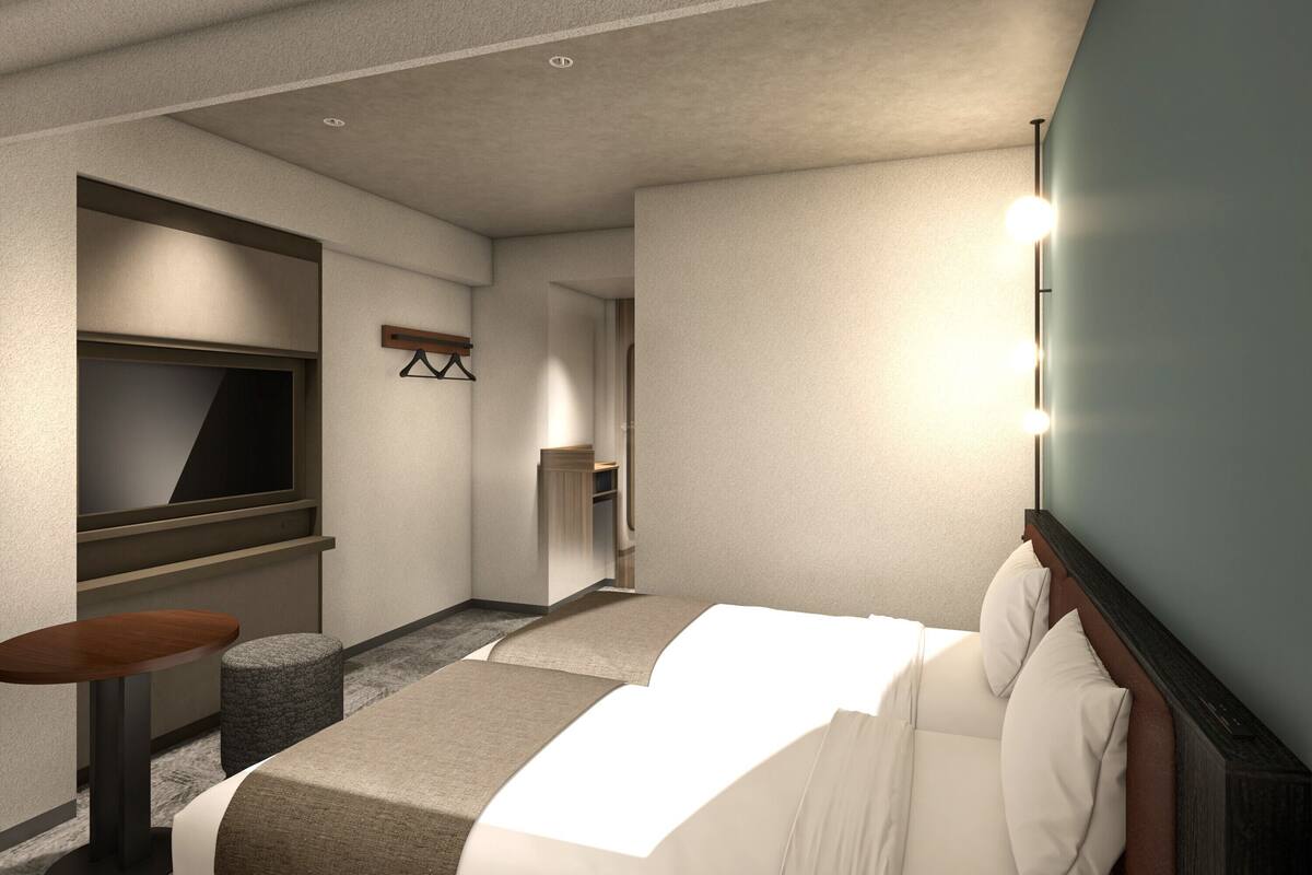A hotel room with a bed, a TV, a small table, and a seating area.