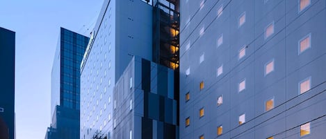 A modern hotel with a glass facade, multiple floors, and a prominent entrance with a canopy.