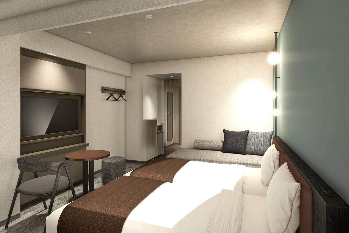 A hotel room with a bed, a TV, a small table, a chair, and a sofa.