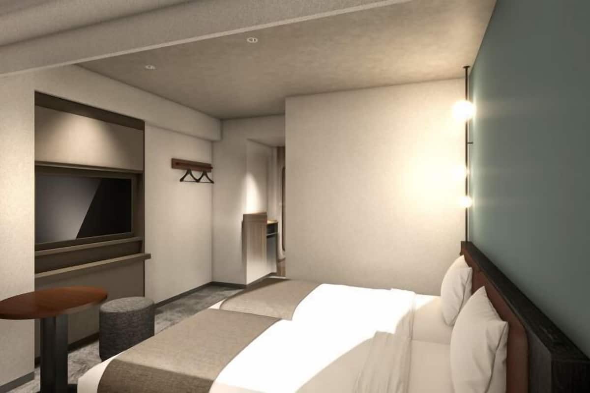 A hotel room with a bed, a TV, a desk, and a chair.