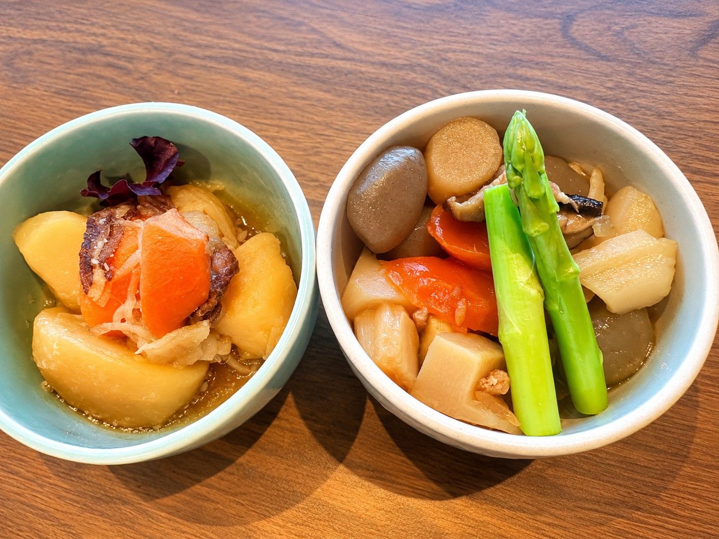 Two bowls of food on a wooden table.
