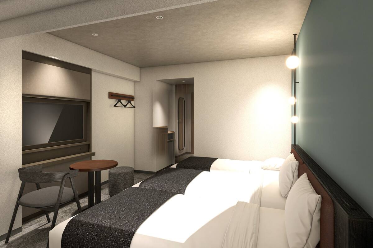 A hotel room with a bed, a TV, a small table, a chair, and a mirror.