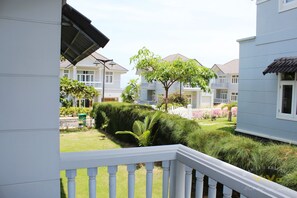 A residential area with white houses, a well-maintained lawn, and a white picket fence.
