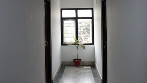 A hallway with a potted plant, a window, and a ceiling fan. - Kathmandu Friendly Home (Kathmandu)