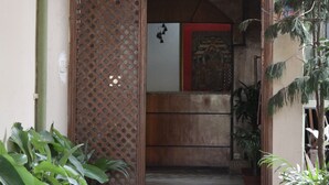 The entrance to Kathmandu Friendly Home Hotel with a wooden lattice door and potted plants. - Kathmandu Friendly Home (Kathmandu)