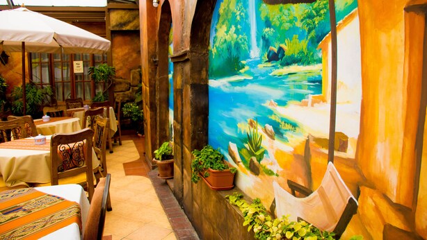 Un comedor interior con mesas, sillas y plantas en macetas.