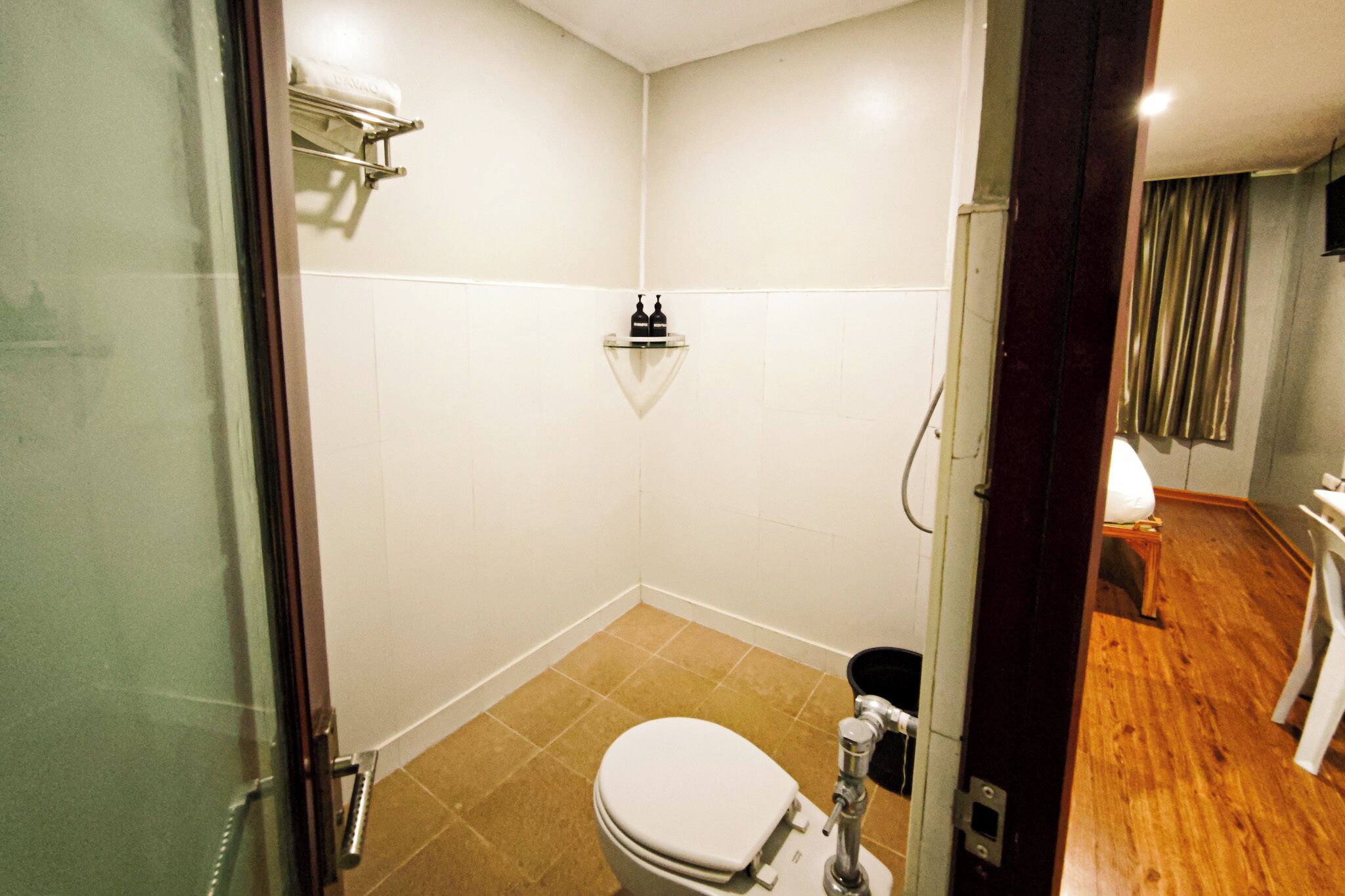 A small, compact bathroom with a toilet, a shower, and a glass-enclosed sink.