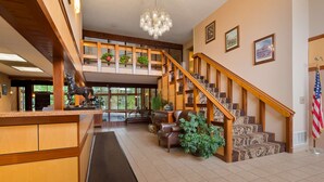 Un vestíbulo espacioso con una escalera de madera, un candelabro y un mostrador de recepción.