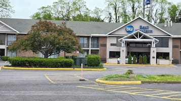 A Best Western hotel with a parking lot and a large tree in front.