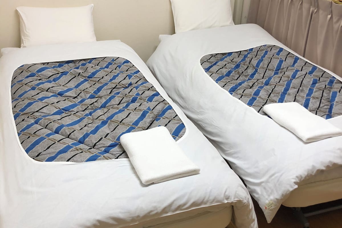 A double bed with a patterned bedspread and a white pillow.