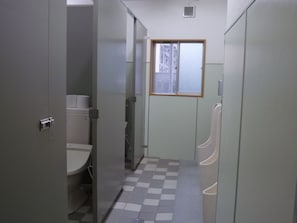 A compact bathroom with a checkered floor, toilet, urinal, and window.
