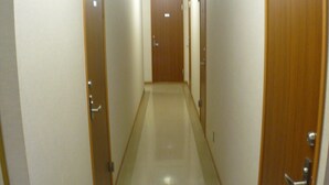 Un pasillo estrecho y bien iluminado con puertas de madera a ambos lados, que conduce a una habitación al final.
