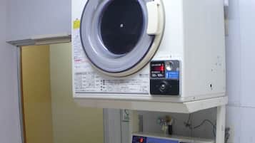 A laundry area with a front-loading washing machine, a stacked dryer, and a coin-operated washer.