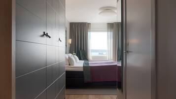 Ein modernes Hotelzimmer mit Bett, Kleiderschrank und Meerblick.
