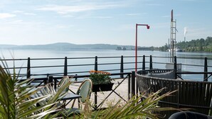 A lakeside patio with outdoor seating, a railing, and a view of the water and distant hills. - Elite Plaza Hotel, Örnsköldsvik (Ornskoldsvik)