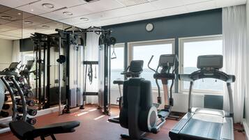 A gym with various exercise equipment, large windows, and a view of the city.