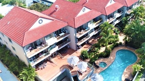 Un hotel de varios pisos con tejados de tejas rojas, balcones y una piscina.