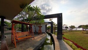 Un espace extérieur aménagé avec des sièges, une balançoire, une petite table et un élément décoratif aquatique.