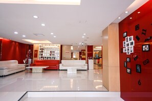 A modern lobby with a white sofa, red accents, and a glass coffee table. - i-Deal Hotel (Taichung)