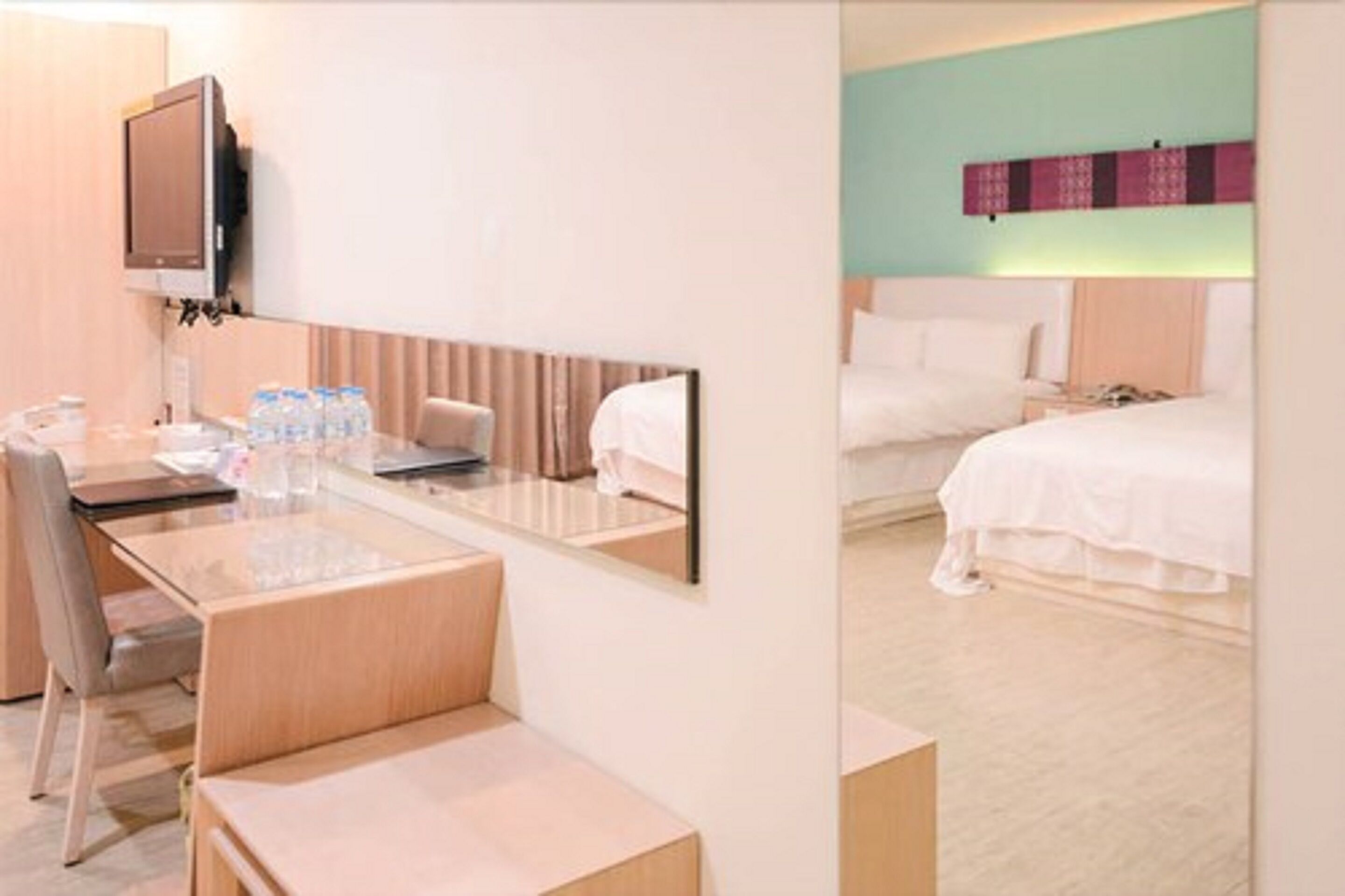A hotel room with a desk, chair, and a bed.