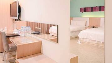 A hotel room with a desk, chair, and a bed.