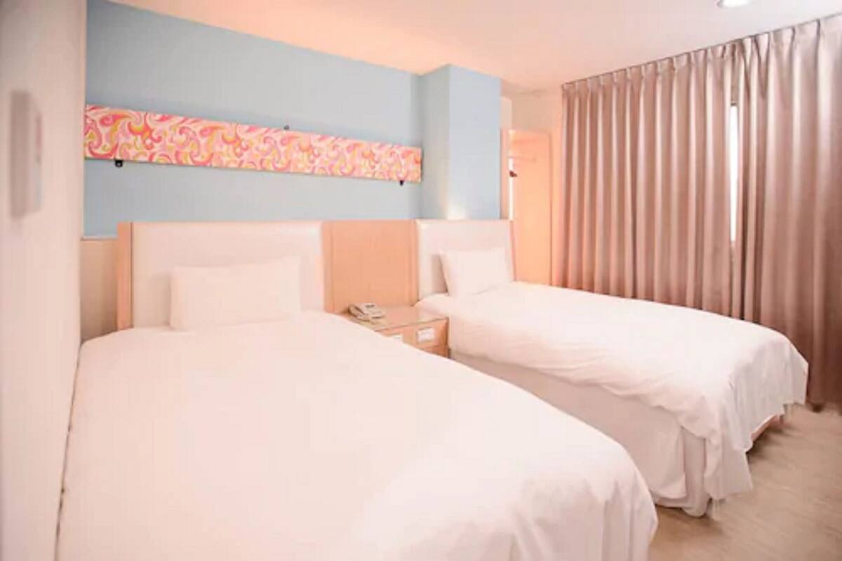 A hotel room with two beds, a nightstand, a phone, and a decorative wall piece.