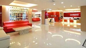 Un vestíbulo amplio con un sofá rojo, una recepción y una exhibición de diversos objetos.