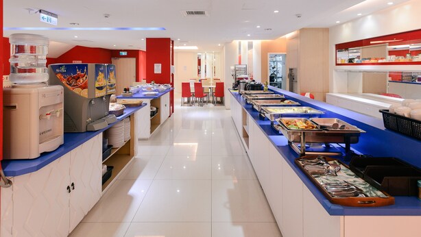 Una cafetería moderna con un mostrador azul, dispensadores de agua y diversas opciones de comida.