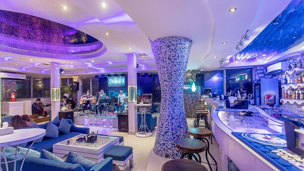 A modern bar area with a unique column, seating, and a bar counter.