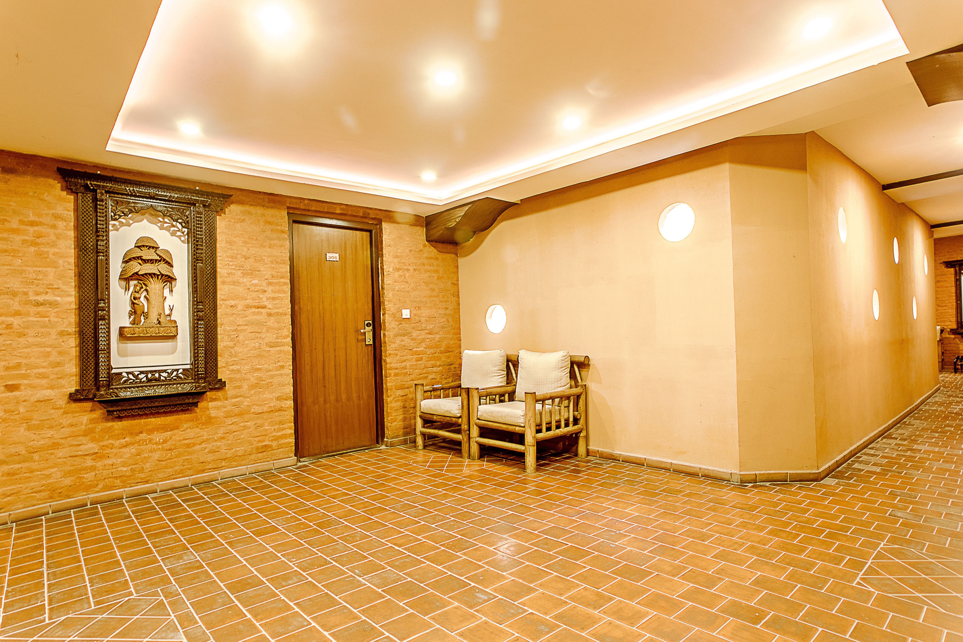 A hallway with a tiled floor, a wooden door, and a framed picture on the wall.