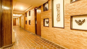 A hotel hallway with a tiled floor, wooden doors, and framed artwork on the walls.