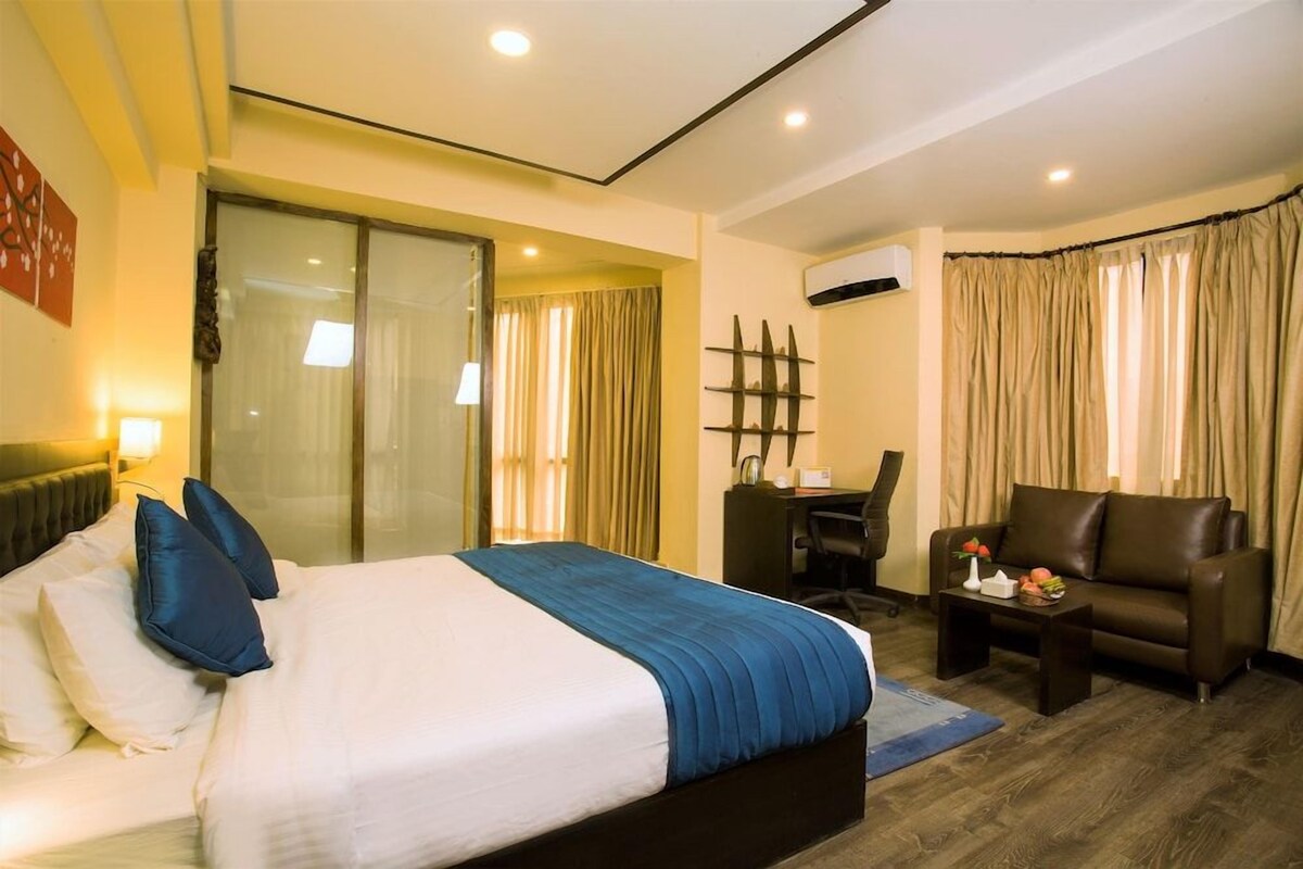 A hotel room with a bed, a desk, a chair, and a sofa.